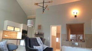 Un salon moderne avec un grand fauteuil, un canapé et une vue sur la cuisine et la salle de bain.