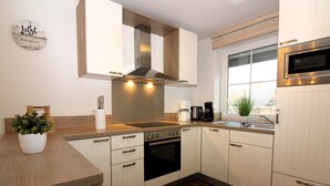 Una cocina moderna con gabinetes blancos, una campana extractora de acero inoxidable, un horno empotrado y una ventana con vistas.
