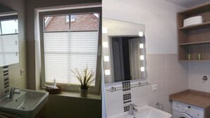 A bathroom with a sink, mirror, and washing machine. - ROB 02 for 6 persons, approx. 78 sqm - Feriendorf Robbenplatte Burhave (1) (Butjadingen)