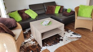 A modern living room with a sectional sofa, two armchairs, a coffee table, and a cowhide rug. - ROB 02 for 6 persons, approx. 78 sqm - Feriendorf Robbenplatte Burhave (1) (Butjadingen)