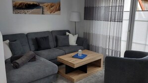 Un salon moderne avec un canapé gris, une table basse en bois et une lampe.
