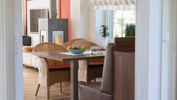 A dining area with wicker chairs, a wooden table, and a bowl of fruit. - ROB 07 for 6 persons, approx. 78 sqm - Feriendorf Robbenplatte Burhave (1) (Butjadingen)