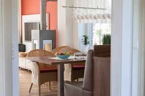 A dining area with wicker chairs, a wooden table, and a bowl of fruit. - ROB 07 for 6 persons, approx. 78 sqm - Feriendorf Robbenplatte Burhave (1) (Butjadingen)
