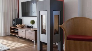 A modern living room with a flat-screen TV, a grey cabinet, a wicker chair, and a wooden entertainment unit. - ROB 07 for 6 persons, approx. 78 sqm - Feriendorf Robbenplatte Burhave (1) (Butjadingen)