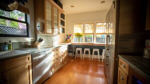Cucina con pensili in legno, frigorifero in acciaio inossidabile e finestra con vista sull'esterno.
