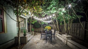 Un patio con pavimento in pietra, un tavolo con sedie e luci decorative.