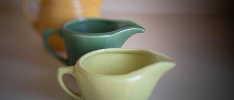 Three ceramic pitchers of different colors on a flat surface.