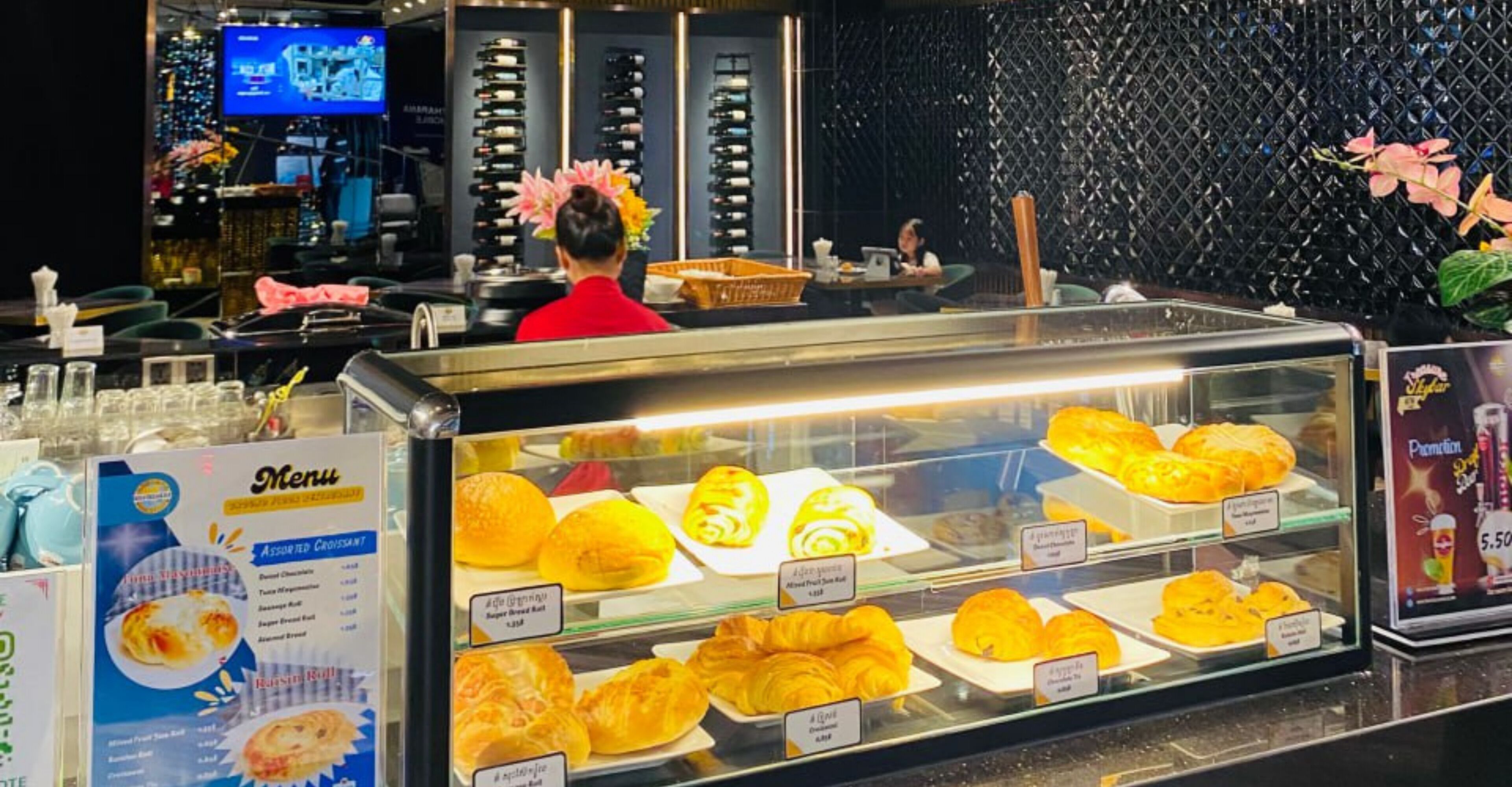 A bakery display case with various pastries and a menu board.