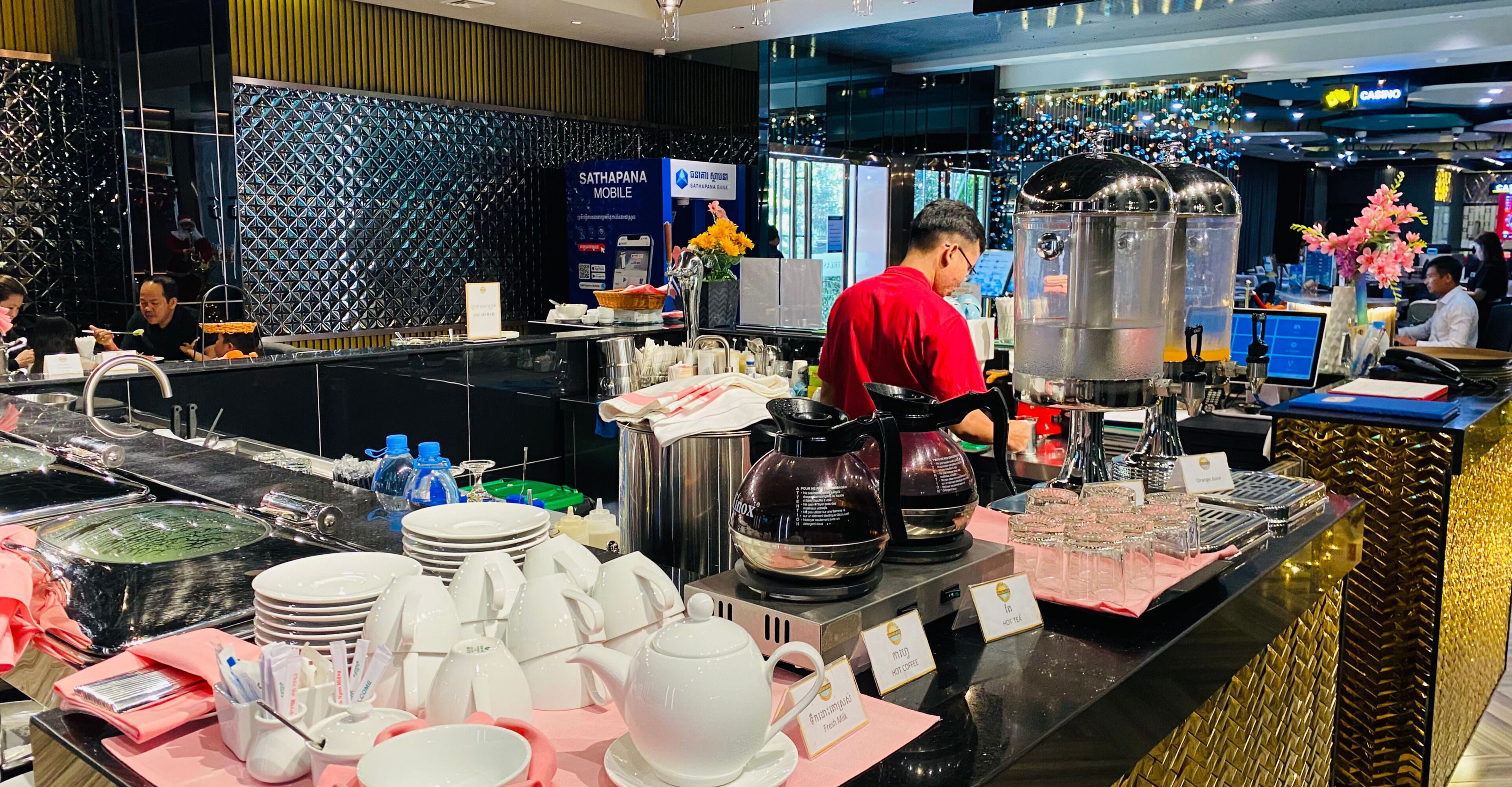 A hotel lobby with a reception desk, a coffee station, and a decorative wall.
