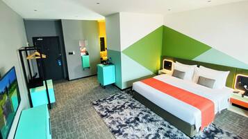 Ein Hotelzimmer mit Bett, Schreibtisch, Stuhl, Fernseher und einem durch eine offene Tür einsehbaren Badezimmer.