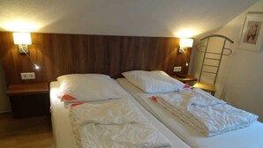 A twin room with two beds, wooden headboard, bedside lamps, and a ladder on the wall. - ROB 10 for 6 people, approx. 78 sqm - holiday village Robbenplatte Burhave (2) (Butjadingen)