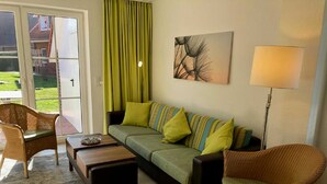 A living room with a sofa, two armchairs, a coffee table, a floor lamp, and a painting on the wall. - ROB 10 for 6 people, approx. 78 sqm - holiday village Robbenplatte Burhave (2) (Butjadingen)
