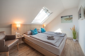 A modern bedroom with a skylight, a bed with blue pillows, a bedside table with a lamp, and a radiator.
