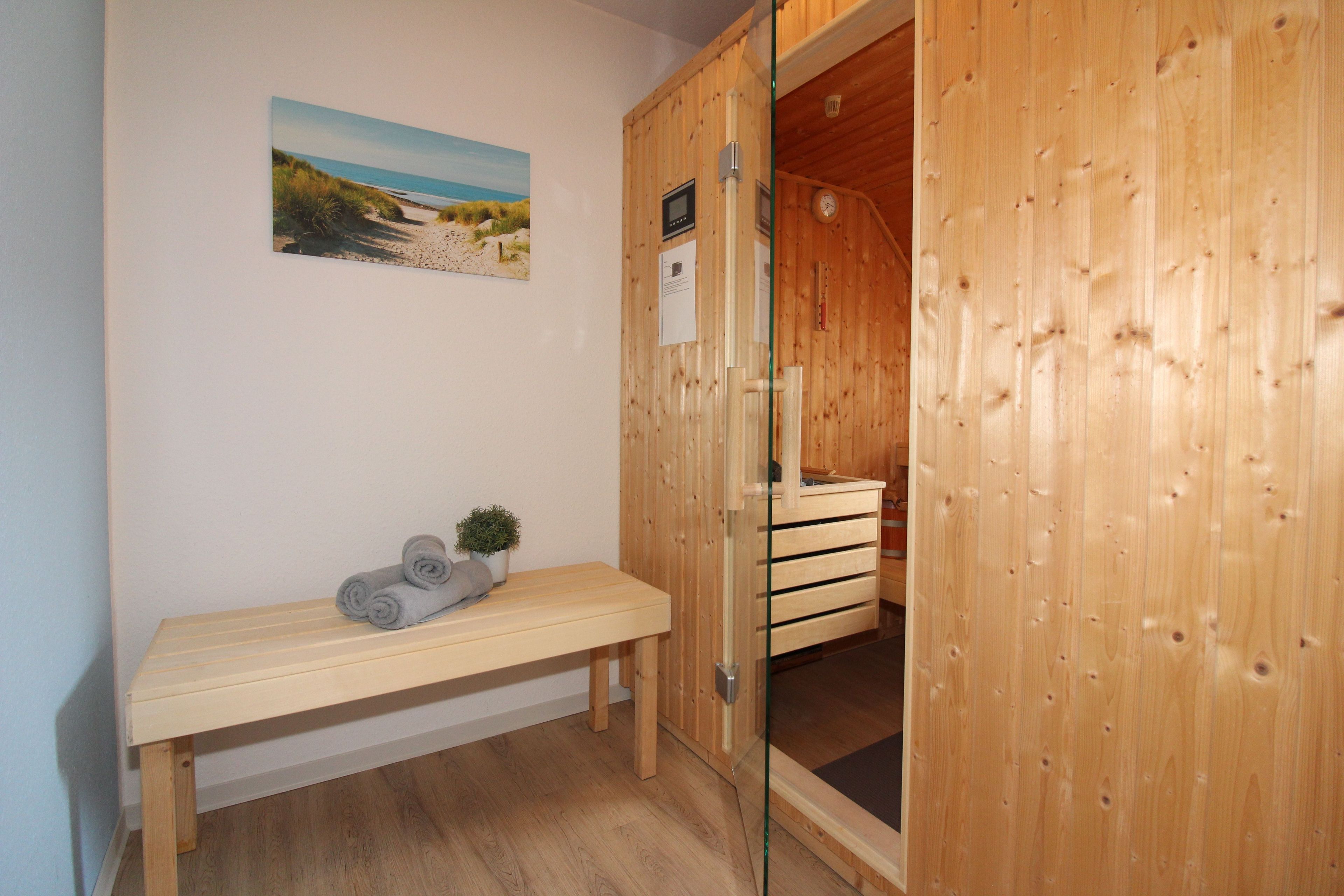 A wooden room with a bench, a small plant, and a painting on the wall.