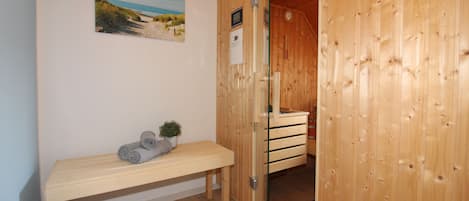 Ett rum med träpanel, en bänk, en liten växt och en tavla på väggen.