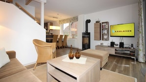A modern living room with a sofa, a coffee table, a TV, and a fireplace. - ROB 15 for 8 persons, approx. 86 sqm - Feriendorf Robbenplatte Burhave (2) (Butjadingen)