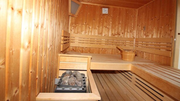 A wooden sauna with benches and a stone basin. - ROB 20 for 8 persons, approx. 86 sqm, pets, sauna - Feriendorf Robbenplatte (Butjadingen)