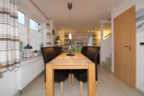 En matplats med ett träbord och svarta stolar, ett element och ett fönster med gardiner.