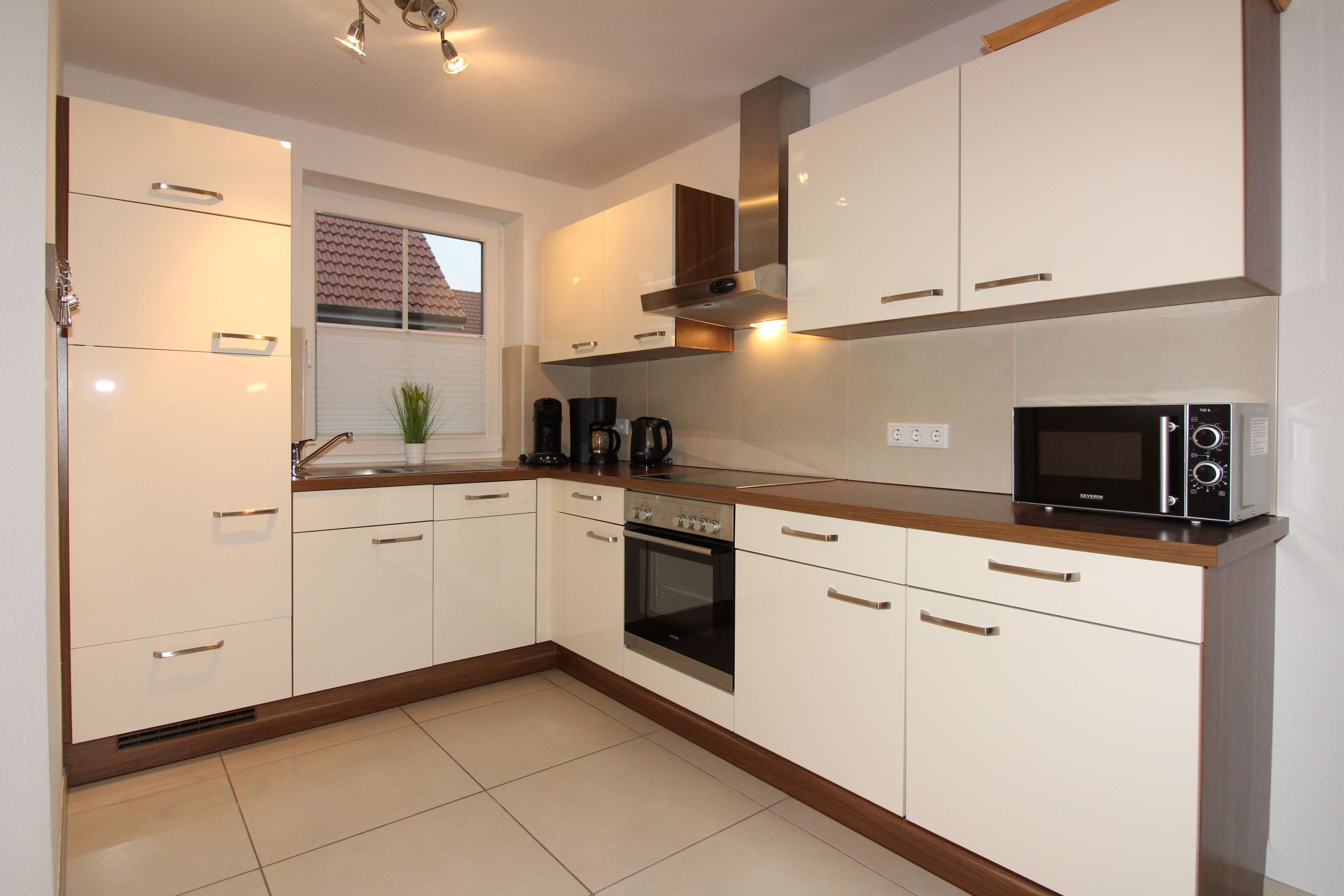A modern kitchen with white cabinetry, a built-in oven, a microwave, and a coffee maker.
