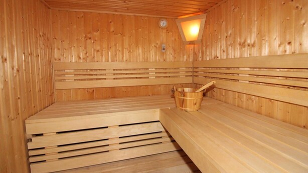 A wooden sauna with benches and a wooden bucket. - ROB 19 for 6 persons, approx. 86 sqm, sauna - Feriendorf Robbenplatte Burhave (3) (Butjadingen)