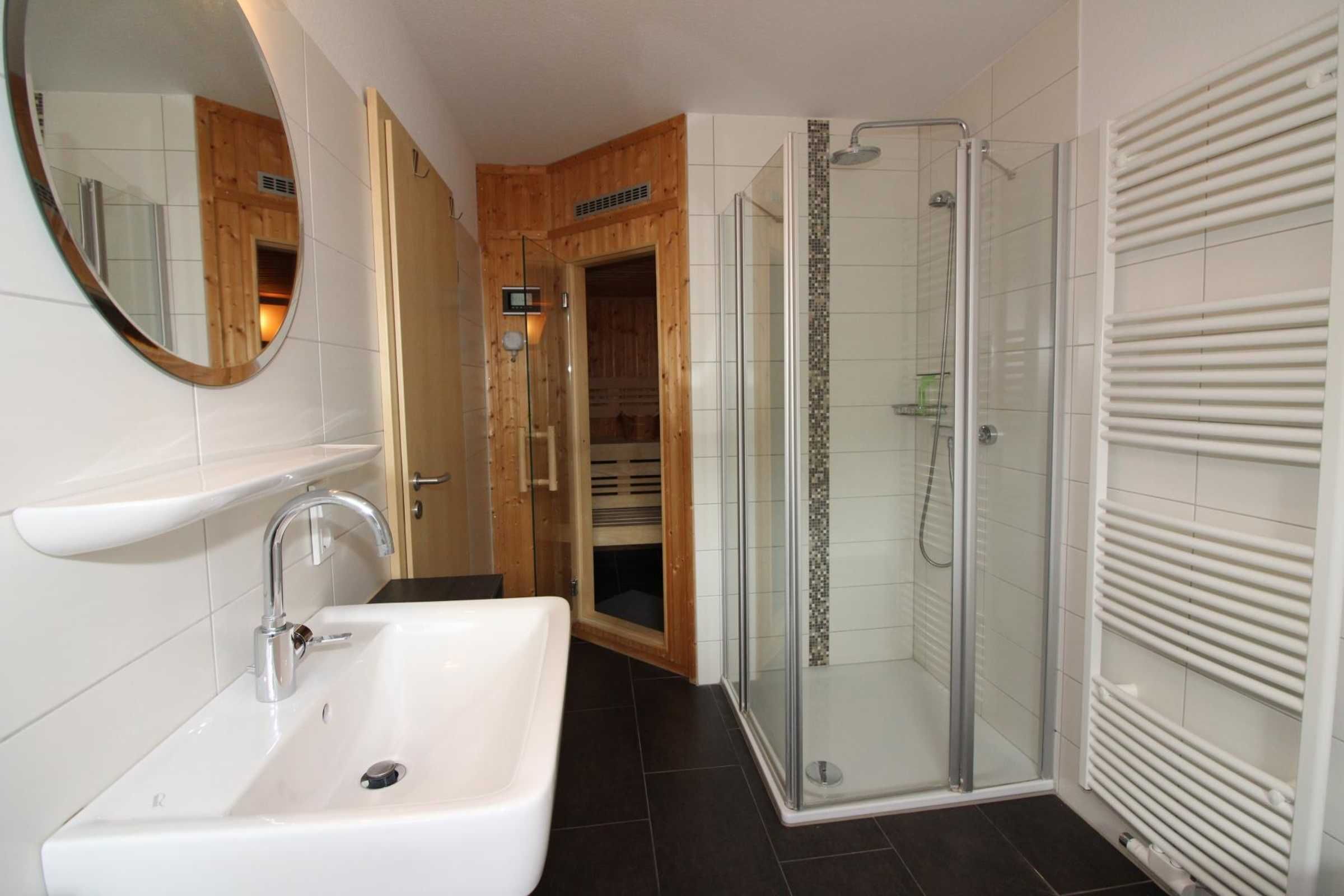 A bathroom with a white sink, mirror, and glass shower enclosure.