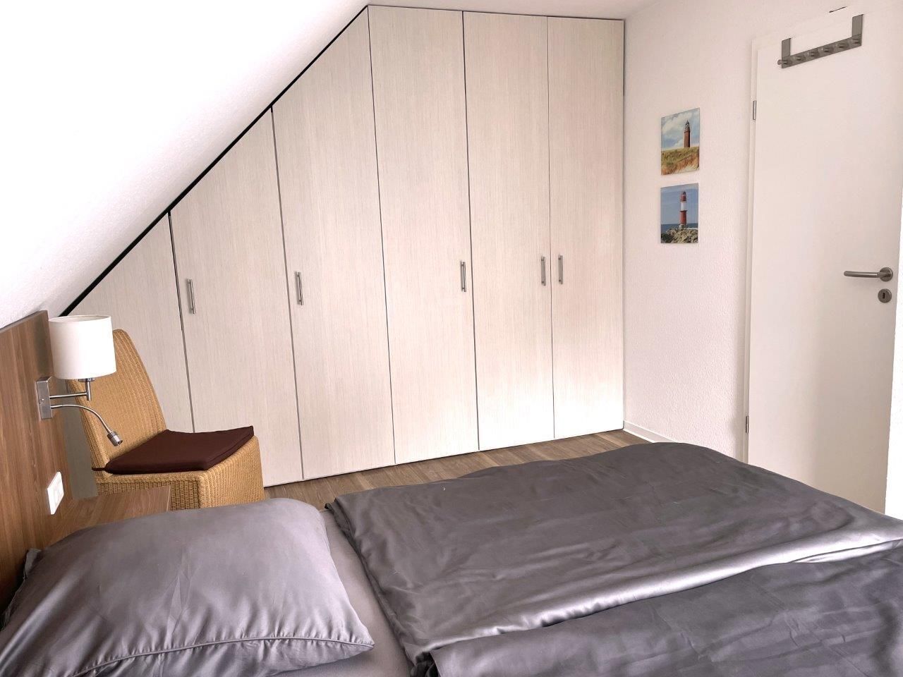 Ein Schlafzimmer mit Bett, Stuhl, Kleiderschrank und einer Tür.