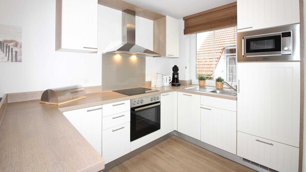 A modern kitchen with white cabinets, a stainless steel range hood, a built-in microwave, and a wooden countertop. - ROB 17 for 6 persons, approx. 86 sqm, pets - Feriendorf Robbenplatte Burhave (Butjadingen)