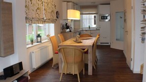 Una cucina funzionale con zona pranzo, caratterizzata da un tavolo in legno, sedie in vimini e un lampadario.