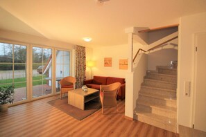 Ein modernes Wohnzimmer mit Holzboden, einer Couch, einem Couchtisch und einer Treppe, die zu einer oberen Etage führt.