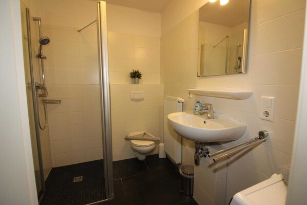 Ein Badezimmer mit Dusche, Toilette, Waschbecken und Spiegel.