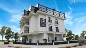 A multi-story hotel with balconies, a prominent sign for 'REFINN HOTEL', and a clear blue sky with birds in the background. - Ref Inn Hotel (Ordu)