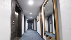 A modern hotel hallway with a carpeted floor, a large mirror, and an elevator. - Ref Inn Hotel (Ordu)