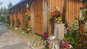 A wooden building with large doors, a stone pathway, and flower arrangements. - Apartment 3 - Holiday apartments Godewind (Zinnowitz)