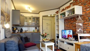 Una sala de estar con un sofá, una mesita con una cesta y un televisor.