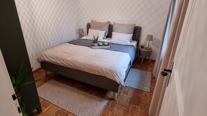 A bedroom with a bed, bedside tables, a hanging light fixture, and a patterned rug. - Spacious vacation apartment for 2 to 4 people surrounded by nature (Feldkirch)