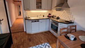 A modern kitchen with white cabinets, a wooden countertop, and a black hanging light fixture. - Spacious vacation apartment for 2 to 4 people surrounded by nature (Feldkirch)