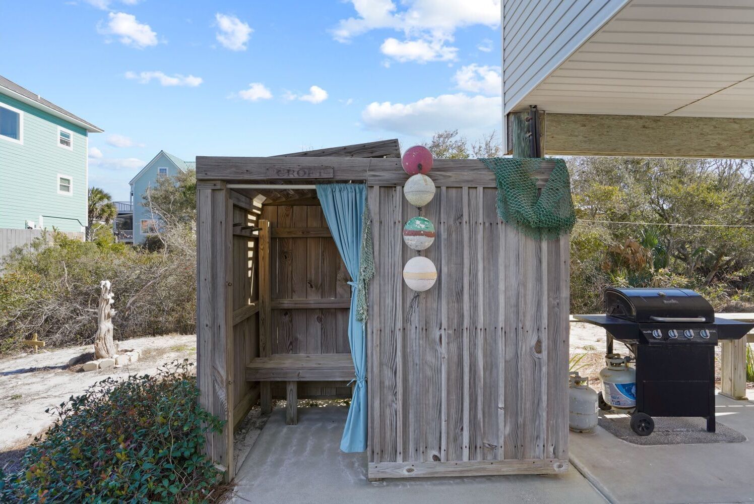 A wooden structure with a blue curtain, a grill, and a gas tank.