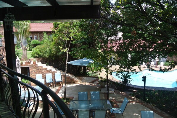A poolside area with outdoor seating and a view of a building in the background. - Farmers Folly Guest House (Pretoria)