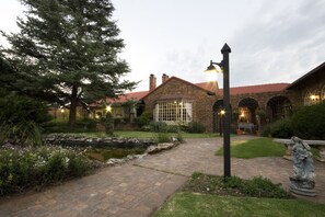 A brick house with a garden, a pond, and a statue. - Farmers Folly Guest House (Pretoria)