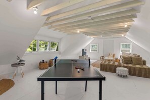 Ein geräumiges Loft mit Tischtennisplatte, Sitzgelegenheit und großen Fenstern.