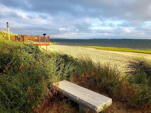 A beach with a wooden structure, a bench, and a view of the sea.