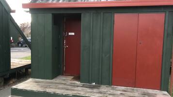 A simple, single-story building with a green exterior and a red door, featuring a flat roof and a small porch area.