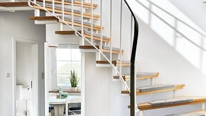 Eine moderne Treppe mit Holzboden und weißen Geländern, die zu einer oberen Etage führt.