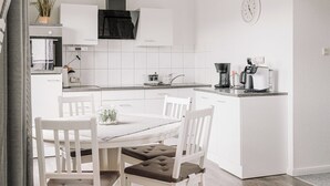 Eine moderne Küche mit weißen Schränken, einem Esstisch mit Stühlen und einer Kaffeemaschine.