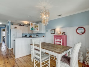 A kitchen with white cabinets, a wooden dining table, and a pink sideboard. - Ocean Views, Steps to Beach, Heated Pool Access! (Tybee Island)