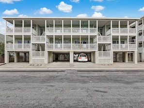 A multi-story building with balconies and a parking garage. - Ocean Views, Steps to Beach, Heated Pool Access! (Tybee Island)