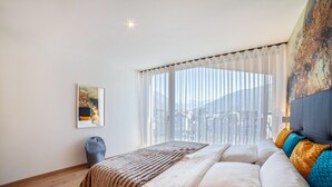 Ein Schlafzimmer mit einem Bett, einem Vorhangfenster, einem Bild an der Wand und einer Lampe.