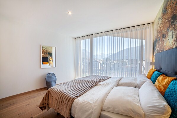 Une chambre à coucher avec un lit, une fenêtre avec des rideaux, un tableau au mur et une lampe.