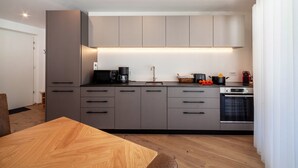 Eine moderne Küche mit grauen Schränken, einem Holzespeisetisch und einem eingebauten Backofen.