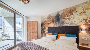A modern bedroom with a large bed, a wooden wardrobe, and a mural on the wall.